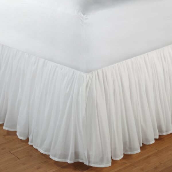 A voile white bed skirt matches white bedding in a romantic bedroom.