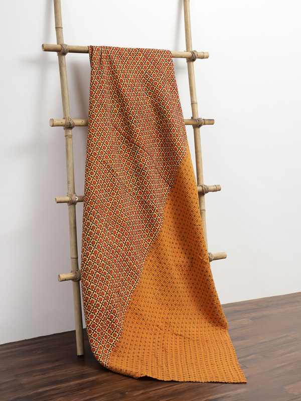 Orange quilted sari throw on a bamboo trellis stand