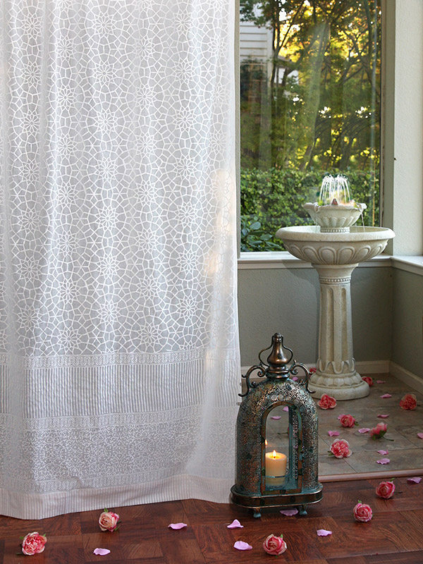 White sheer curtains with a Moroccan style pattern hang at the window.