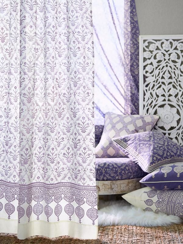 lilac color pillows piled near a window with white and purple curtains in a romantic style elegant floral pattern