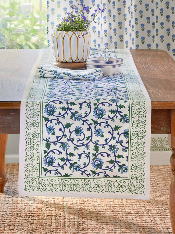 a fresh blue, white, and green spring table runner holds spring decor on the dining table