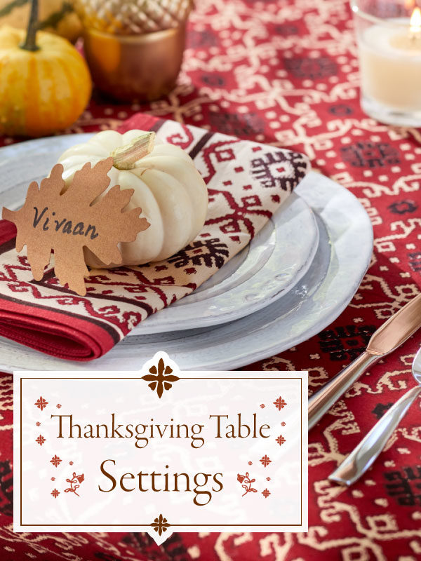 red tablecloth, white pumpkin, name card on place setting, banner that says Thanksgiving table settings