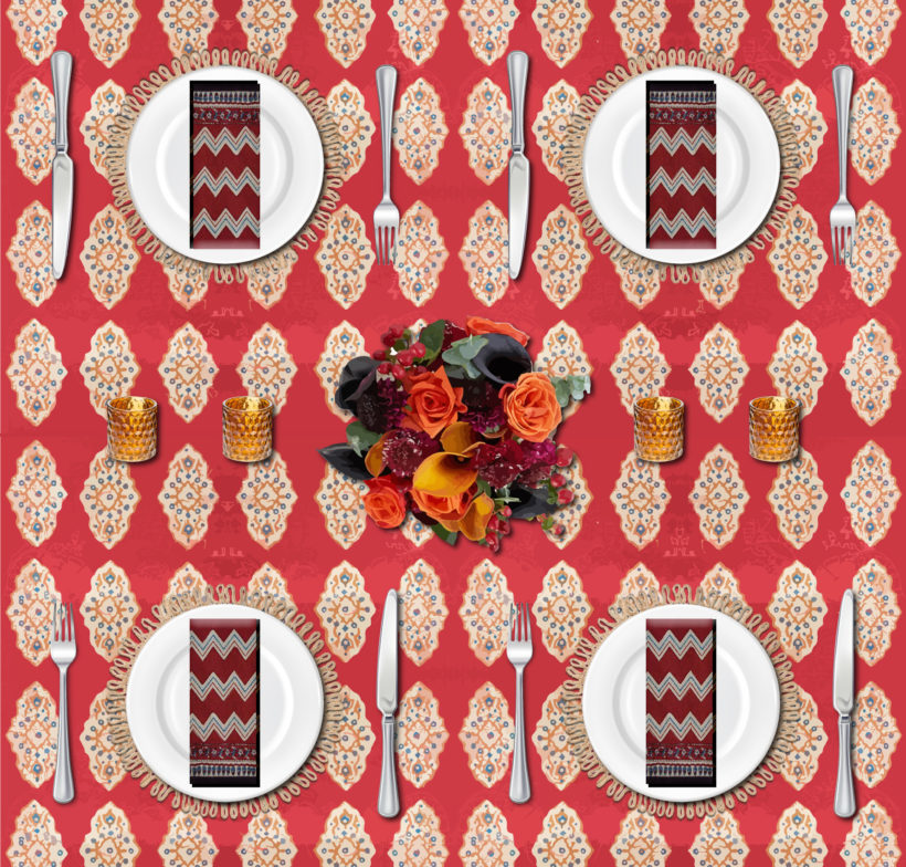 red Thanksgiving tablecloth with boho table setting of dark roses and amber glass votive holders