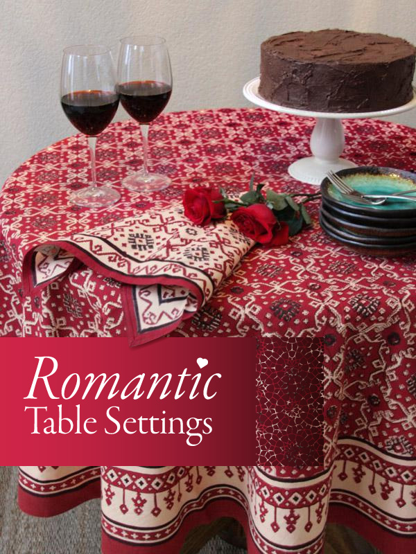 A red Valentine tablecloth set for a romantic table setting with red wine, roses, cloth napkins, and chocolate cake