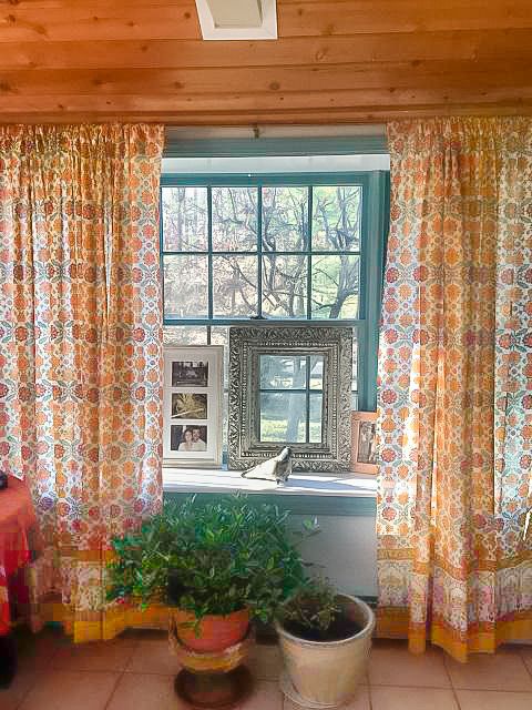 boho curtains with orange floral print, plants, and Indian mirror