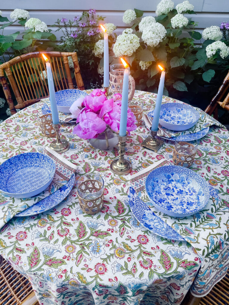 white and pink and blue tablecloth with blue china and pink peonies and candles