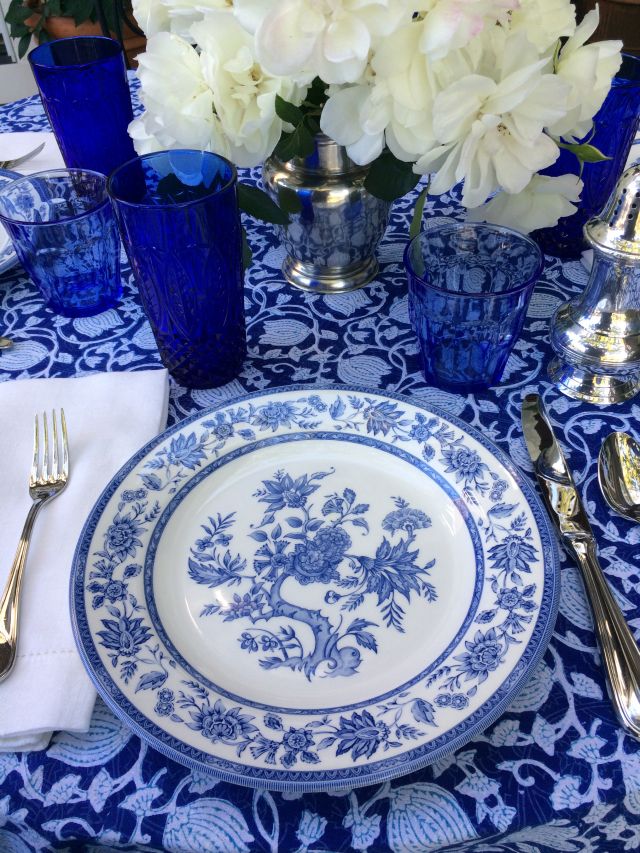 blue floral tablecloth at an elegant table setting with white flowers and silver