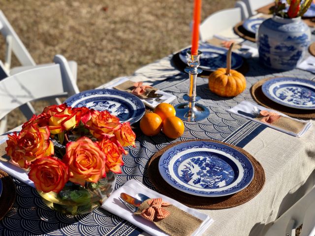 cream and blue table runner with orange flowers and pumpkins for Thanksgiving