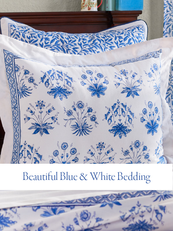 beautiful blue and white bedding on banner over a floral pillow in those same colors