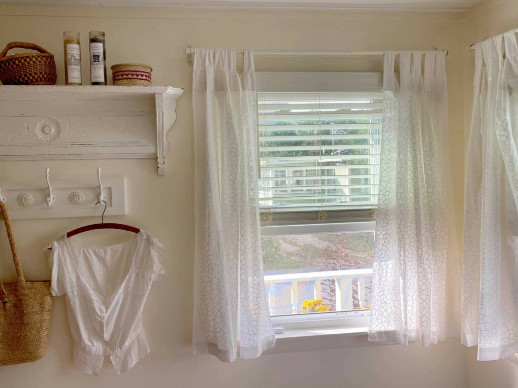 cottage farmhouse laundry room with white sheer curtains at the window