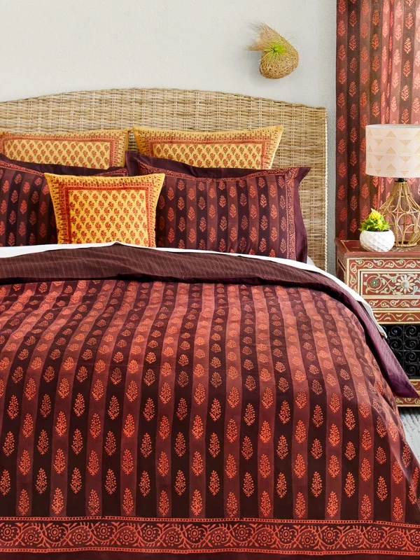 Bohemian orange and brown duvet cover with Mehndi symbols and matching pillows, shams, and curtains in a white-wall bedroom