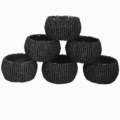 A closeup of six black, beaded napkin rings arranged in a pyramid structure against a white background
