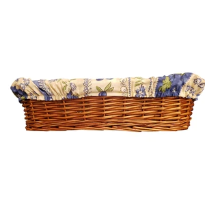 A long, brown, French wicker basket for bread lined with a cotton fabric covered in fruits, flowers, and leaves