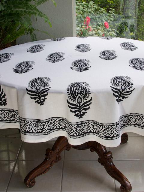 Paisley Au Lait round tablecloth featuring black paisley motifs on a white cotton background covering a dark brown table