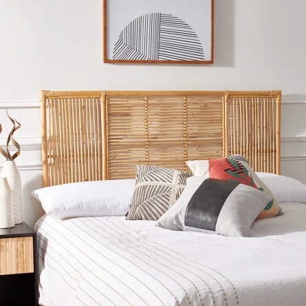 A wicker headboard on a bed with white and black bedding