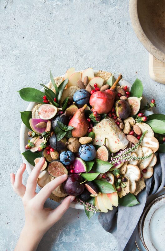Photograph of a fruit-filled platter with decorative leaves and flower springs