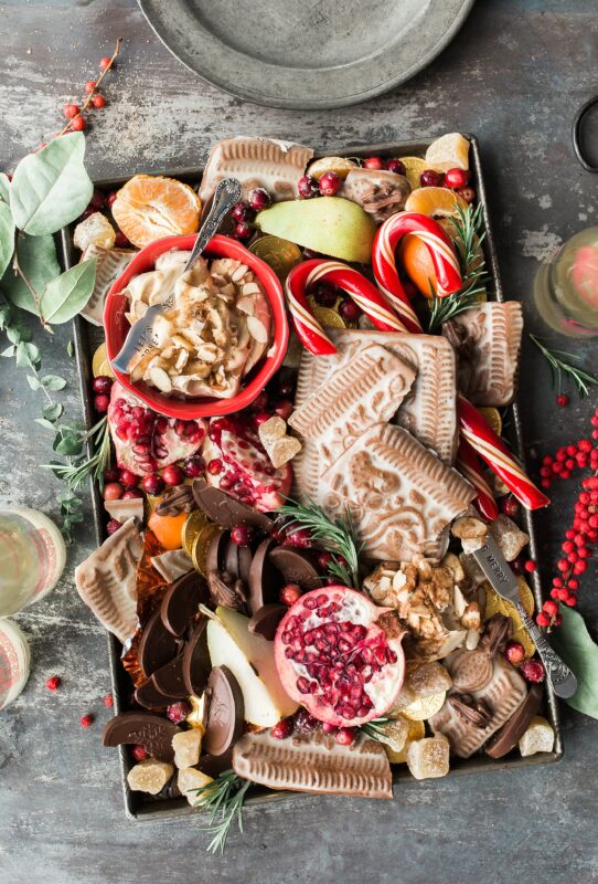 Example of Christmas charcuterie board filled with cookies, pomegranates, chocolates, and other small ingredients