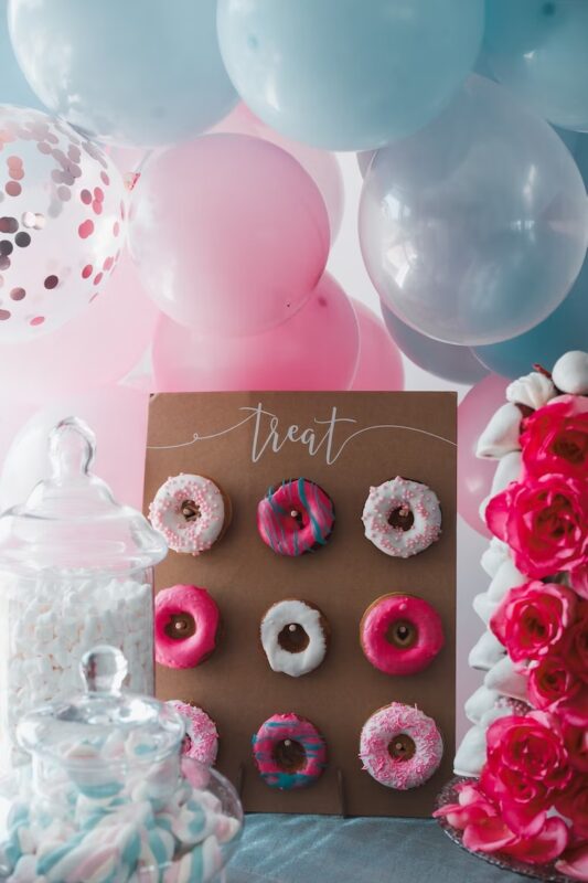 A mini donut wall on a table with jars of marshmallows for an engagement party idea for a dessert theme