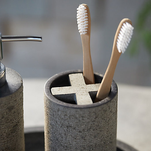 A stone toothbrush holder holding two bamboo tothbrushes