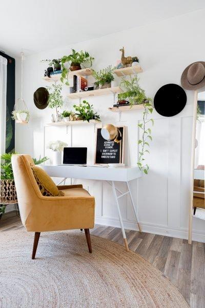 Shelf decor full of plants and an inspirational quote in a home office with a gold armchair
