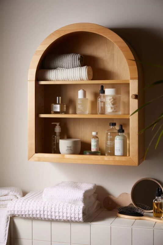 Wooden arched mason wall shelf filled with skincare products and extra towels