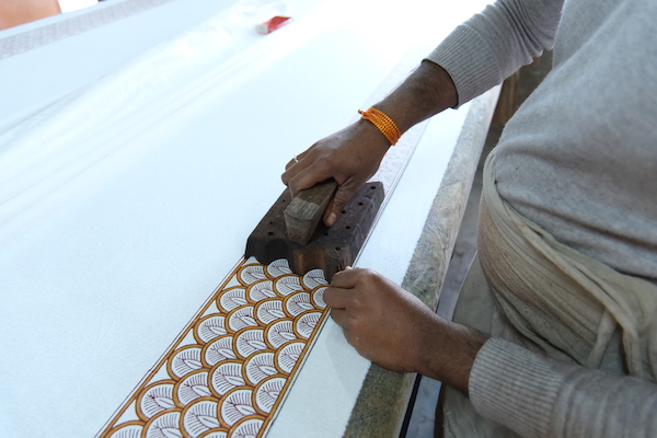Photograph of artisan stamping a border pattern for an elegant pattern