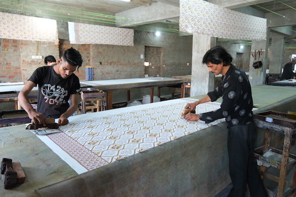 Photograph of artisans using wood block printing to create floral textiles
