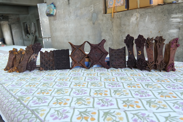 Photograph of hand carved wooden blocks on a table covered with a floral fabric