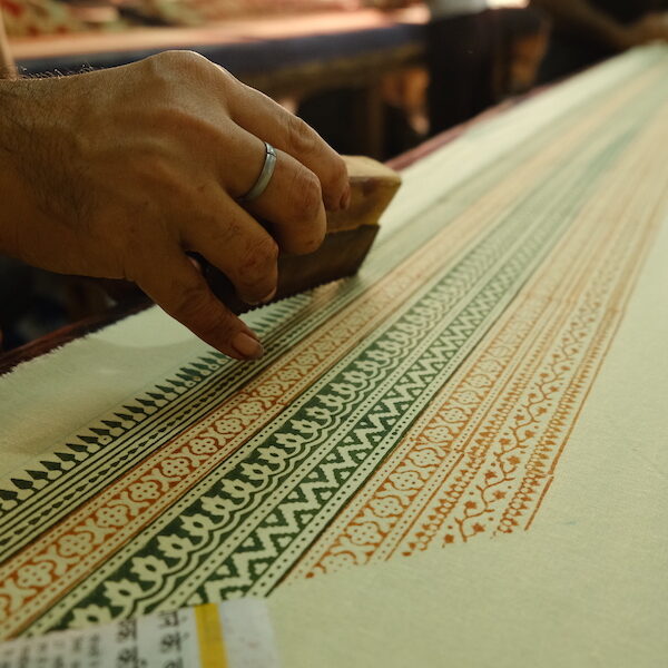 Image of an artisan block printing the border of our Christmas fabric print