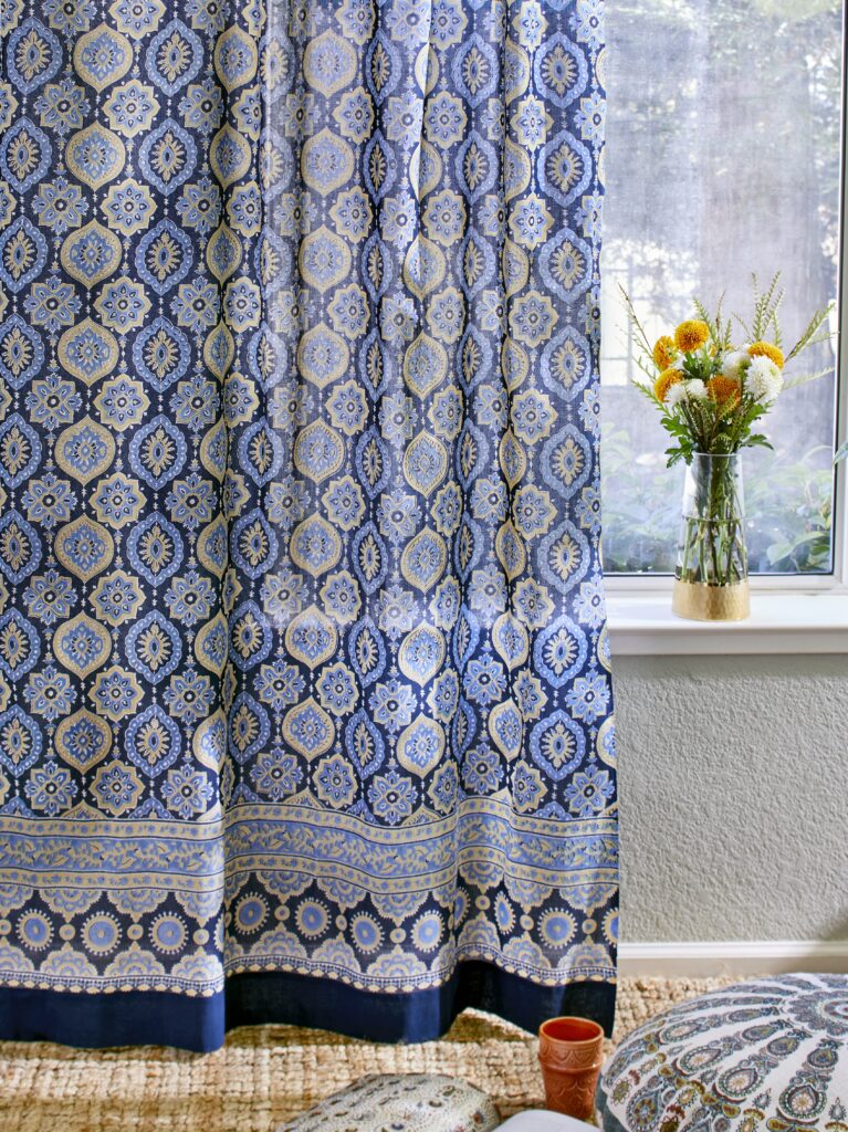 Photograph of a Moroccan curtain with a Moroccan pouf in the foreground, showcasing how portable furniture is a small guest room idea for maximizing hospitality