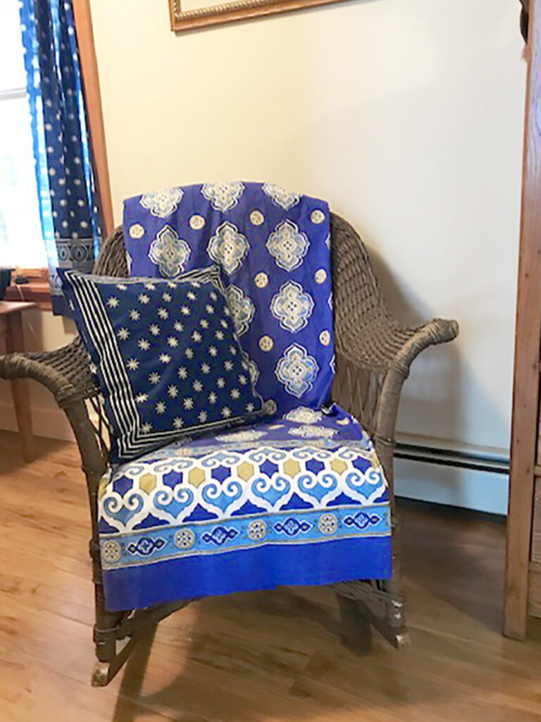 Photograph of neutral living room that uses a pop of color through a blue throw blanket and blue throw pillow on a chair