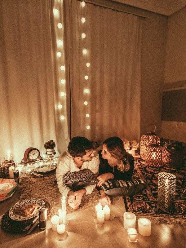 Photograph of man and woman at home in a romantically lit living room to give an idea for an at home Valentine's Day idea for couples