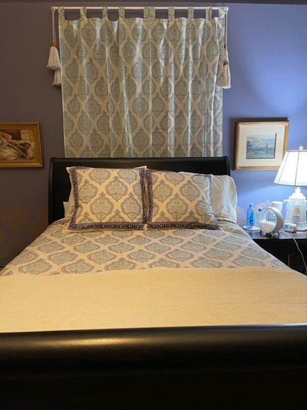 Photograph of a bedroom with a digital alarm block and lamp on the bedside table, demonstrating small guest room ideas for maximizing hospitality