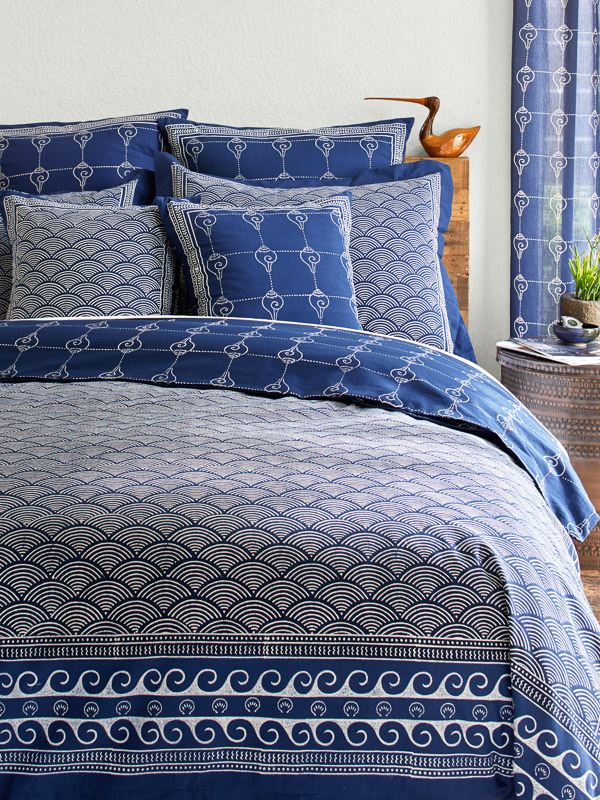 coastal bedding set with navy blue duvet cover, shell pattern border, and wave pattern and shell pillows